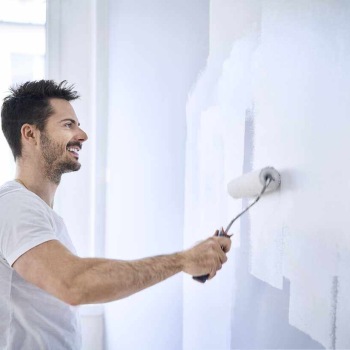 Smiling man painting wall in apartment